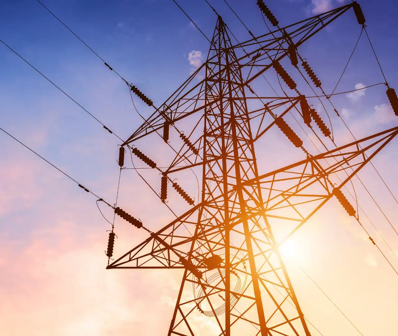 Electricity pylon against vibrant sunset sky